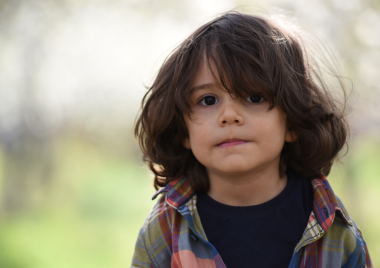 young boy with long hair and neutral expression