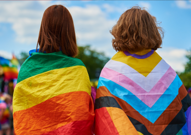 Two teenagers with LGBTQ+ flags around their shoulders