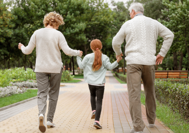 child walking and holding hands of grandparents