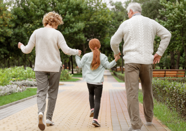 child walking whilst holding grandparents hands