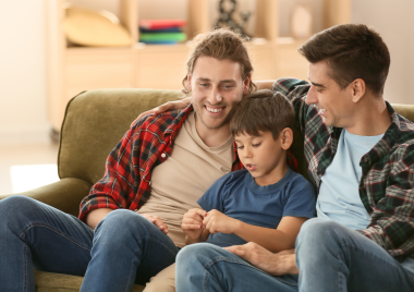 Two men sat on a sofa with boy