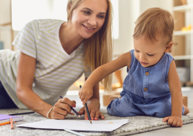 woman smiling at child who is drawing