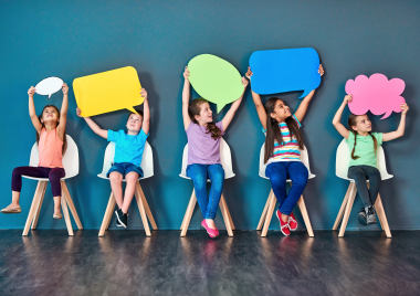 children holding paper cutouts of speech bubbles