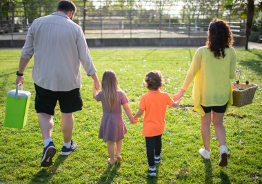 Two parents walking with two children holding hands