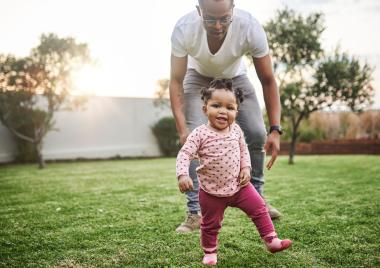 Foster carer supporting a young child to walk
