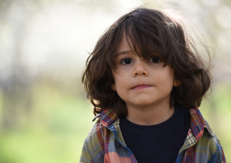 young boy with long hair with neutral expression
