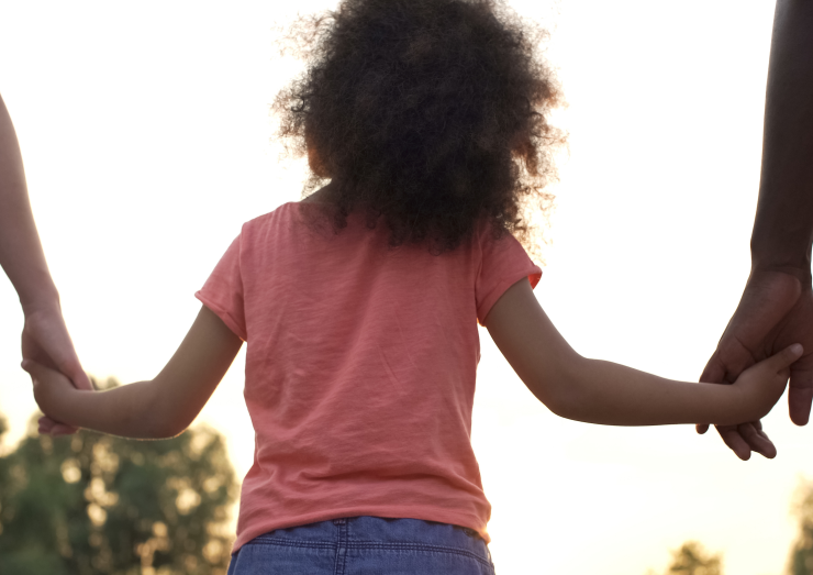 looking at a child holding adults hands with their back to the camera