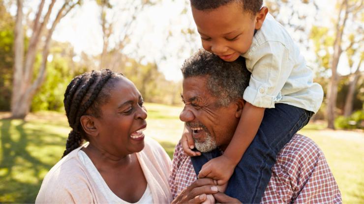 An older couple with a child on their shoulders
